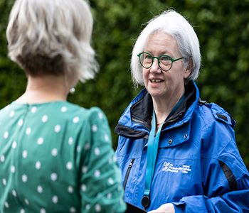A CSO Survey Interviewer speaking with a survey participant in a garden