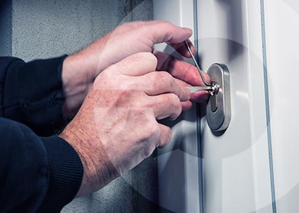 Close up of hands using lock picks to open an outside door lock