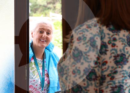 A householder opens the door to a CSO Household Surveys Interviewer on the doorstep